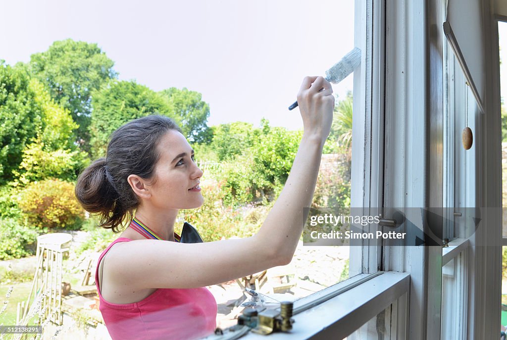 Young woman painting house window