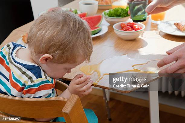 male toddler accidently spilling orange juice at breakfast table - dumb blonde stock pictures, royalty-free photos & images