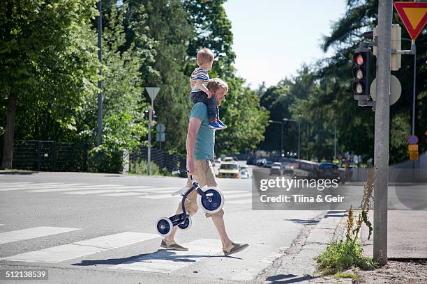 father shoulder carrying toddler son over pedestrian crossing - finland summer stock pictures, royalty-free photos & images