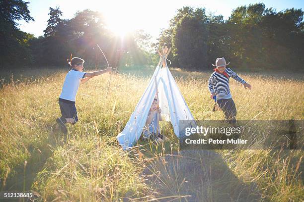 small group of young boys playing around teepee - tipi stock-fotos und bilder