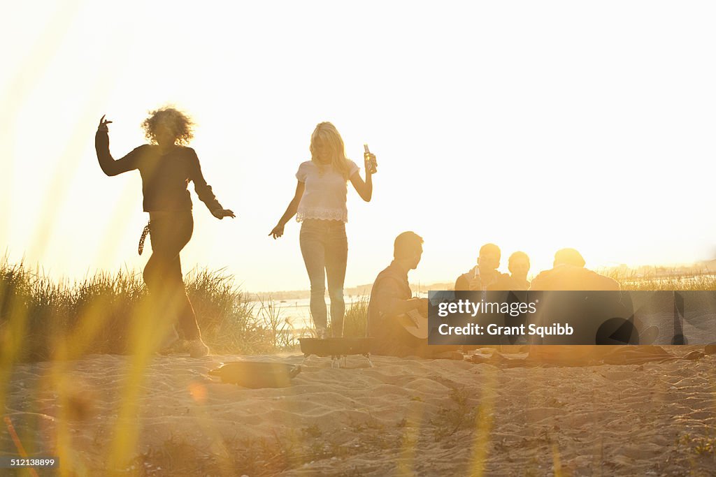 Six adult friends partying at sunset on Bournemouth beach, Dorset, UK