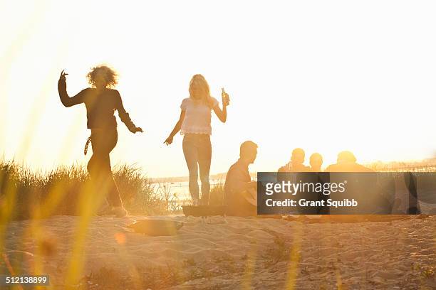 six adult friends partying at sunset on bournemouth beach, dorset, uk - beach party stock pictures, royalty-free photos & images
