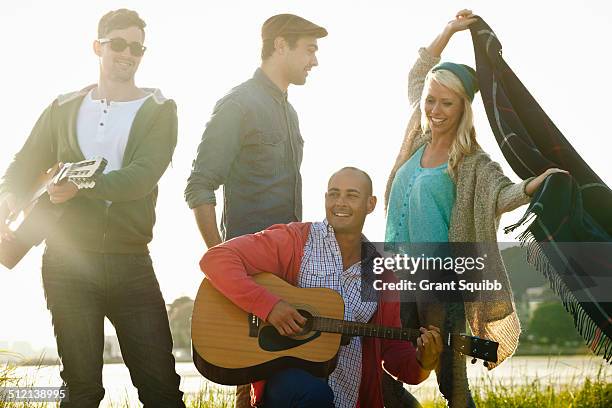 four adult friends with acoustic guitar and picnic blanket on bournemouth beach, dorset, uk - lens flare young people dancing on beach stock pictures, royalty-free photos & images