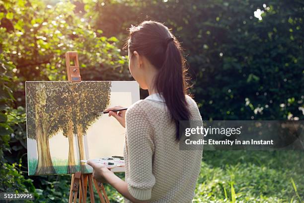 artist painting trees outdoors - female artist painting stock-fotos und bilder