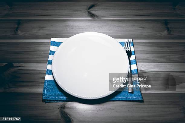 empty plate and fork on a wooden table. - vuoto stock-fotos und bilder