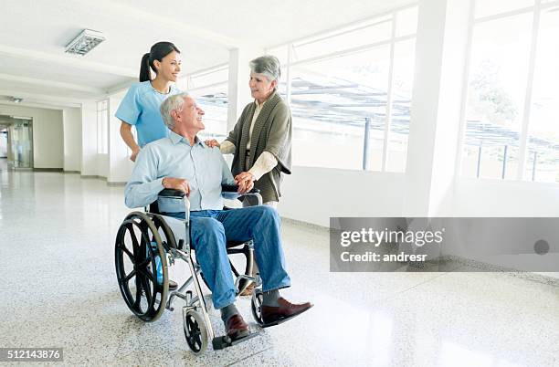 nurse pushing senior man in a wheelchair at the hospital - press screening stock pictures, royalty-free photos & images