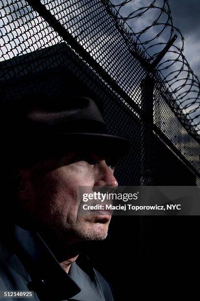 portrait of a man in hat against barbed wire fence - mystery detective stock pictures, royalty-free photos & images