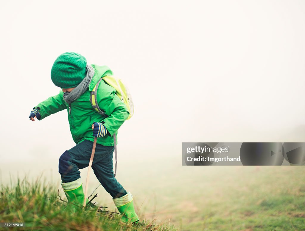 Brave little hiker climbing a hill in mist