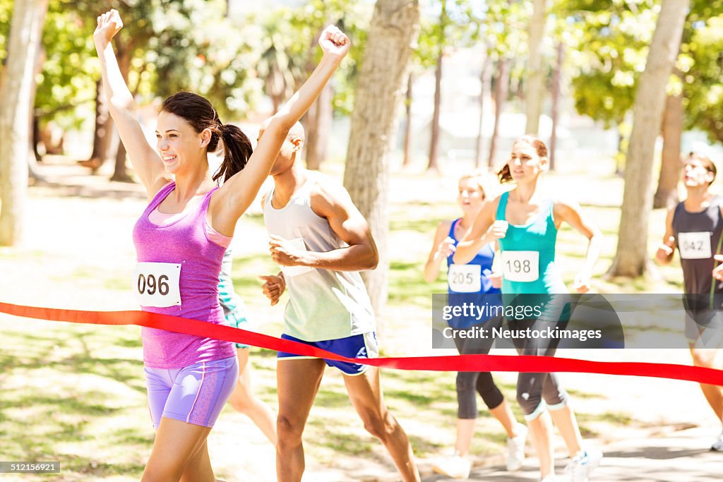 Lächelnd weiblichen Marathon-Läufer Kreuzung Ziellinie
