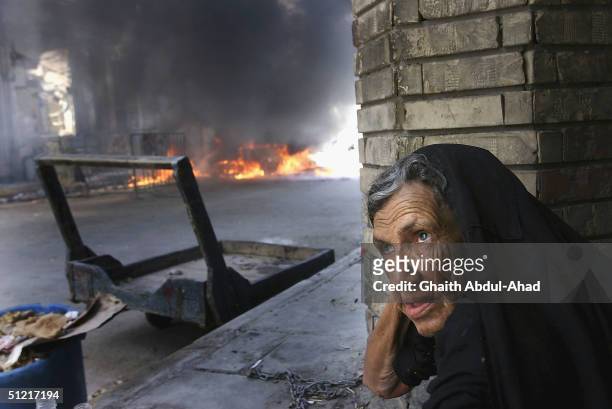 Woman sits in front of a burning car 50 meters away from the shrine of Imam Ali on August 25, 2004 in Najaf, Iraq. The car was hit by US fire in the...