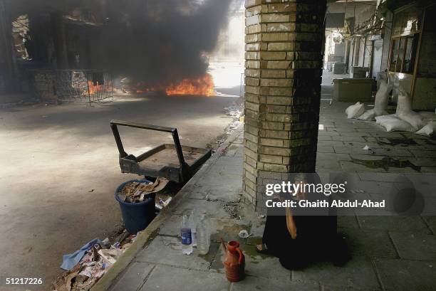 Woman sits in front of a burning car 50 meters away from the shrine of Imam Ali on August 25, 2004 in Najaf, Iraq. The car was hit by US fire in the...