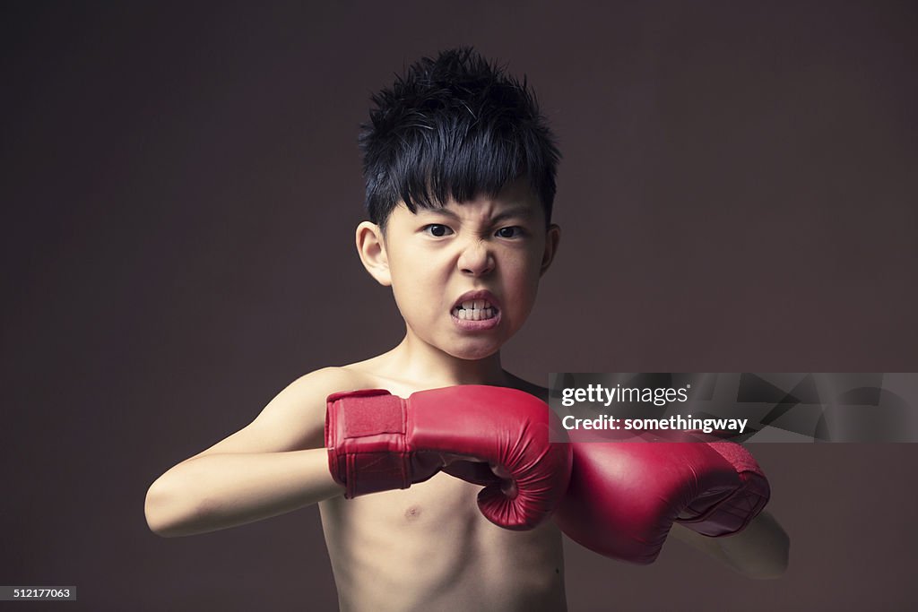 Angry young boy play boxe with gloves