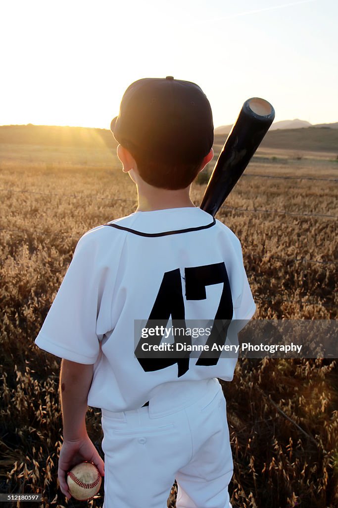 Young baseball player from behind sunset