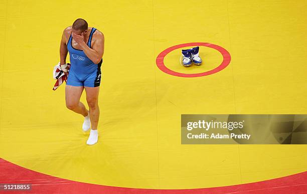 Rulon Gardner of the USA wipes his face as he walks off the mat leaving his shoes behind to signify his retirement after winning the bronze medal...