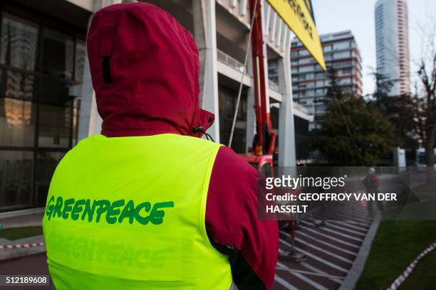 Greenpeace activist watches a banner asking Bollore group CEO Vincent Bollore to stop committing deforestation hung in front of Bollore's...