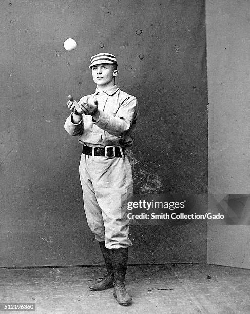 Photographic portrait of Tommy McCarthy wearing a Philadelphia Quakers uniform, in the photograph he is catching a ball that was thrown to him, he...