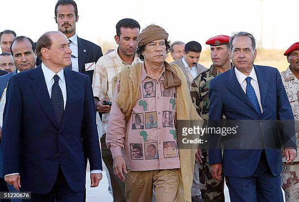 Libyan leader Moamer Kadhafi gestures as Italian Prime Minister Silvio Berlusconi and Italian Interior Minister Giuseppe Pisanu look before their...