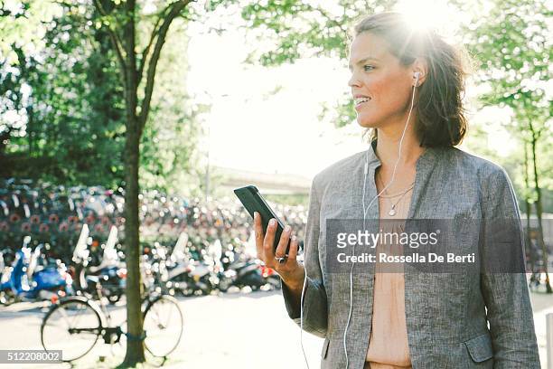 portrait of successful businesswoman using smartphone in urban landscape - amsterdam zuidas stock pictures, royalty-free photos & images