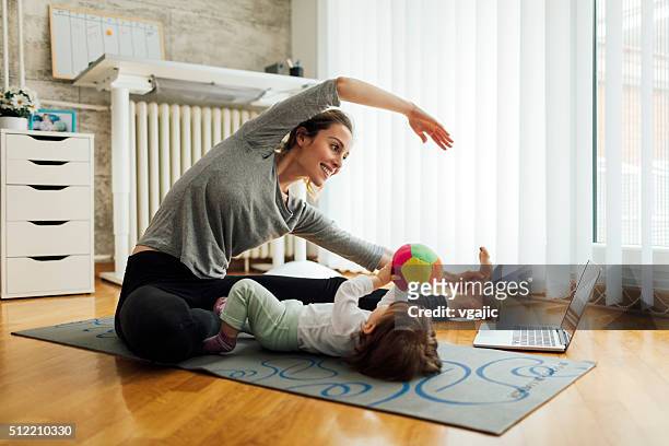 mother exercise with her baby at home - mother and baby and laptop stock pictures, royalty-free photos & images
