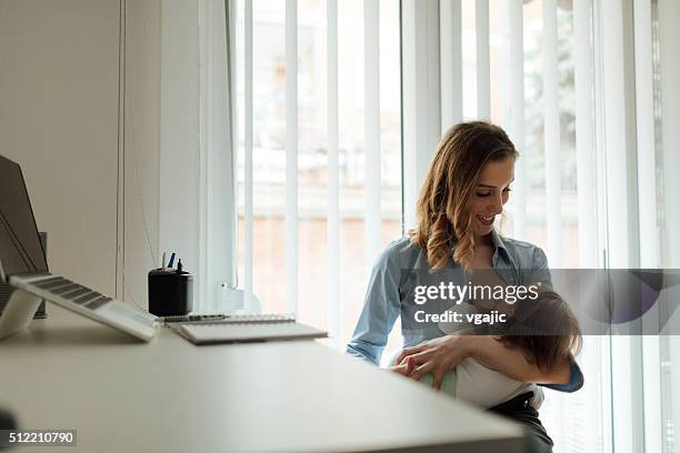 mother working and breastfeeding her baby - leanincollection mother stock pictures, royalty-free photos & images