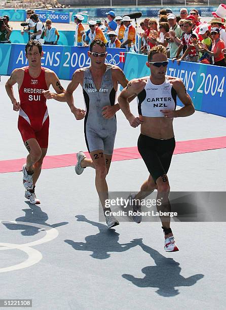 Hamish Carter and Bevan Docherty of New Zealand lead Sven Riederer of Switzerland during the run leg in the men's triathlon on August 26, 2004 during...