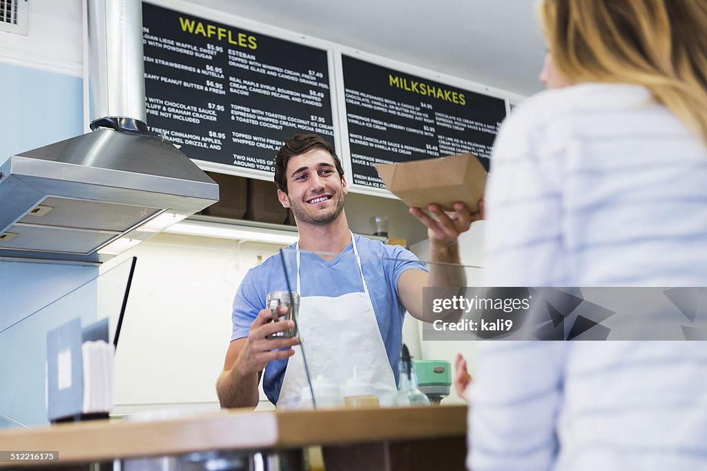 Worker serving customer in waffle shop