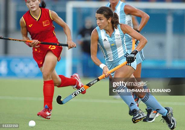 Argentinian hockey player Mariana Gonzalez Oliva drives the ball ahead of China's Zhou Wanfeng during the bronze medal match of the women's hockey...