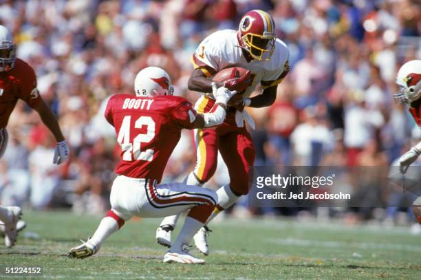 Wide receiver Art Monk of the Washington Redskins protects the ball as he breaks a tackle by safety John Booty of the Phoenix Cardinals during a NFL...