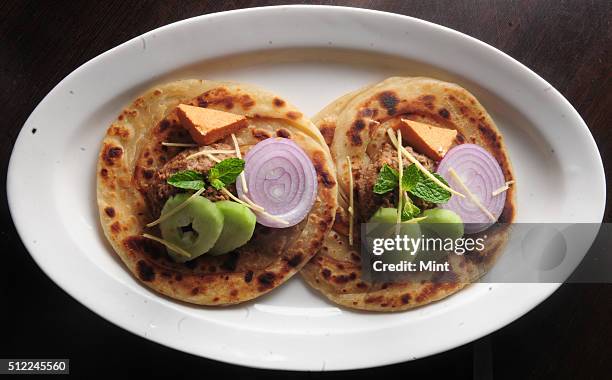 Picture showing special Lucknowi Bengali dish named, Ghutwan Kabab with Paratha served with ginger juliennes cucumber onion and smoked bandel Cheese,...