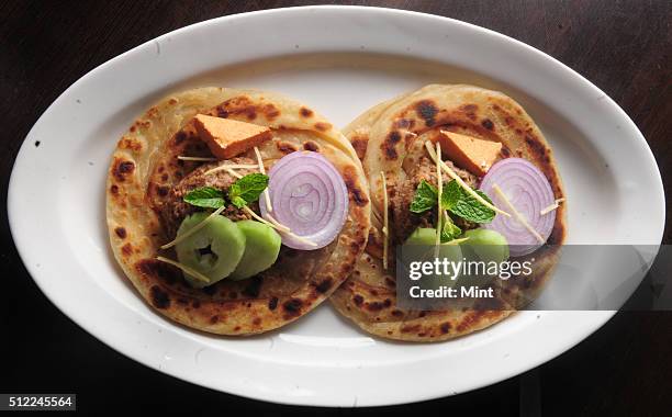 Picture showing special Lucknowi Bengali dish named, Ghutwan Kabab with Paratha served with ginger juliennes cucumber onion and smoked bandel Cheese,...