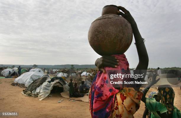 Refugee girls from the strife torn Darfur region of Sudan carry jugs of water back to their shelters at a spontaneous overflow camp August 27, 2004...