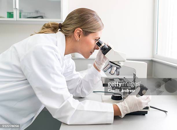 médico haciendo investigación médica en el laboratorio - mirar a través fotografías e imágenes de stock