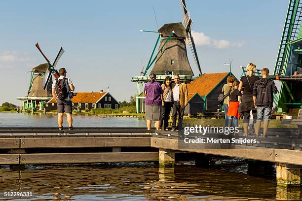 tourists observing windmills from boat quay - zaanse schans stockfoto's en -beelden
