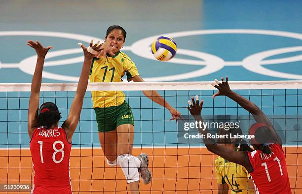 Ana Chagas of Brazil spikes the ball past Zoila Barros Fernandez and Liana Mesa Luaces of Cuba in the women's indoor Volleyball bronze medal match on...