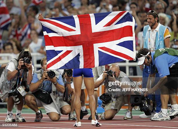 Britain's Kelly Holmes celebrates with her country's flag after winning the gold in the women's 1,500m final ahead of Russia's Tatyana Tomashova and...