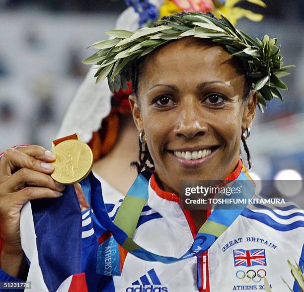Kelly Holmes of Great Britain holds up the gold medal she won in the women's 1500m final, 28 August 2004, during the Olympic Games athletics...