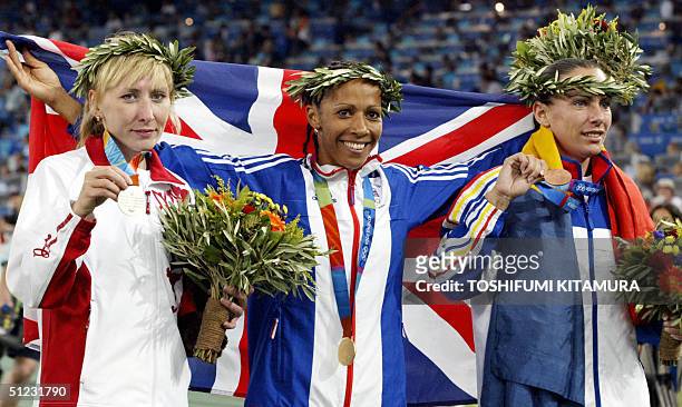 Women's 1500m gold winner Kelly Holmes of Britain , silver winner Tatyana Tomashova of Russia and bronze winner Maria Cioncan of Romania stand on the...