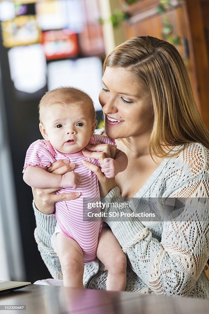 Proud mother holding tiny baby daughter at home