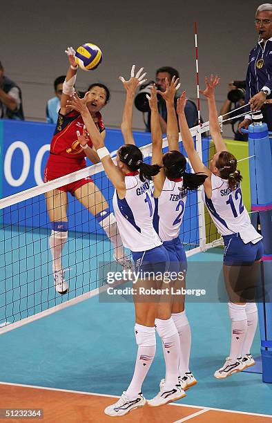 Yuehong Zhang of China sends a shot past Ekaterina Gamova, Irina Tebenikhina and Marina Sheshenina of Russia in the women's indoor Volleyball gold...