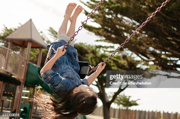 little girl swinging on a swing in a playground - san luis obispo californië stockfoto's en -beelden