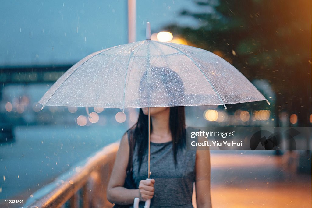 Businesswoman with umbrella looking away at city