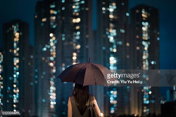 businesswoman overlooking cityscape on a rainy day - protezione foto e immagini stock