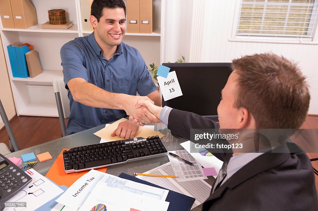 Latin man reviews financial tax documents with accountant. Office.