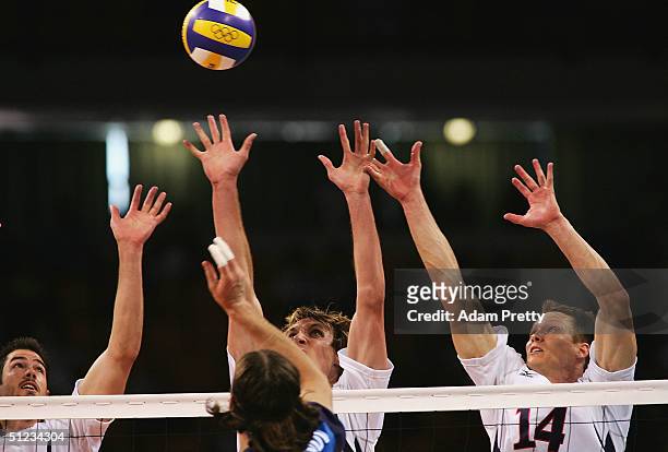 Brook Billings, Ryan Millar and Kevin Barnett of the United States jump for a block over the spike of Sergey Baranov of Russia during the men's...
