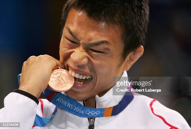 Kenji Inoue of Japan bites his bronze medal after the men's Freestyle wrestling 60 kg bronze medal match on August 29, 2004 during the Athens 2004...