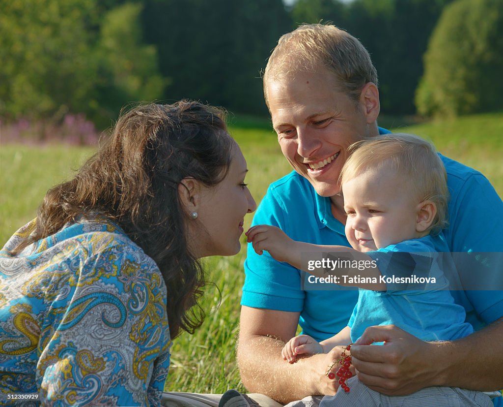 Happy family eating berries on a meadow