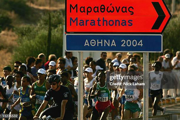 The pack of runners go past a sign indicating the starting line in the men's marathon on August 29, 2004 during the Athens 2004 Summer Olympic Games...