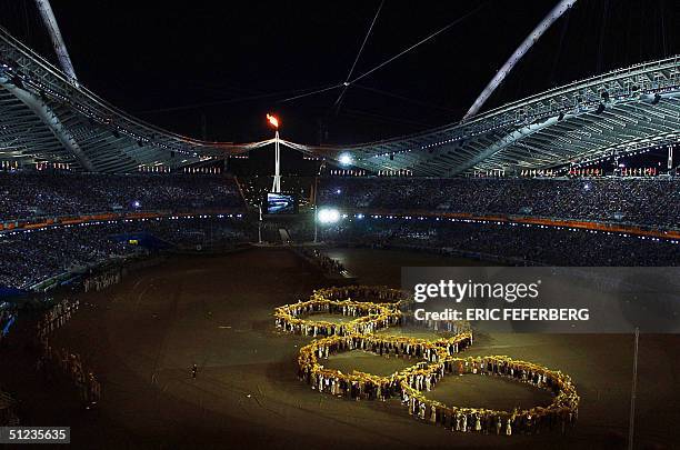 Dancers performing as harvesters form the five Olympic rings after collecting wheat from a spiral wheatfield made up of 45,000 individually 'planted'...