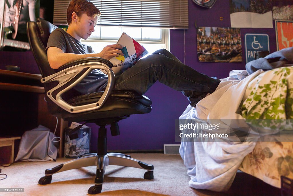 Teenager reading magazine at home