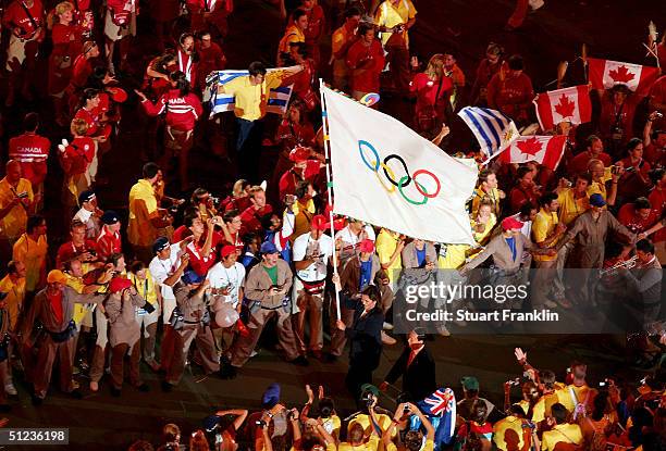 Dora Bakoyianni, mayor of Athens, carries the Olympic flag as she walks next to Wang Qishan, mayor of Beijing, the host city of the Games of the XXIX...